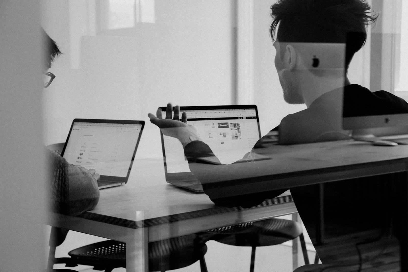 A black-and-white double-exposure photo of people working at laptops