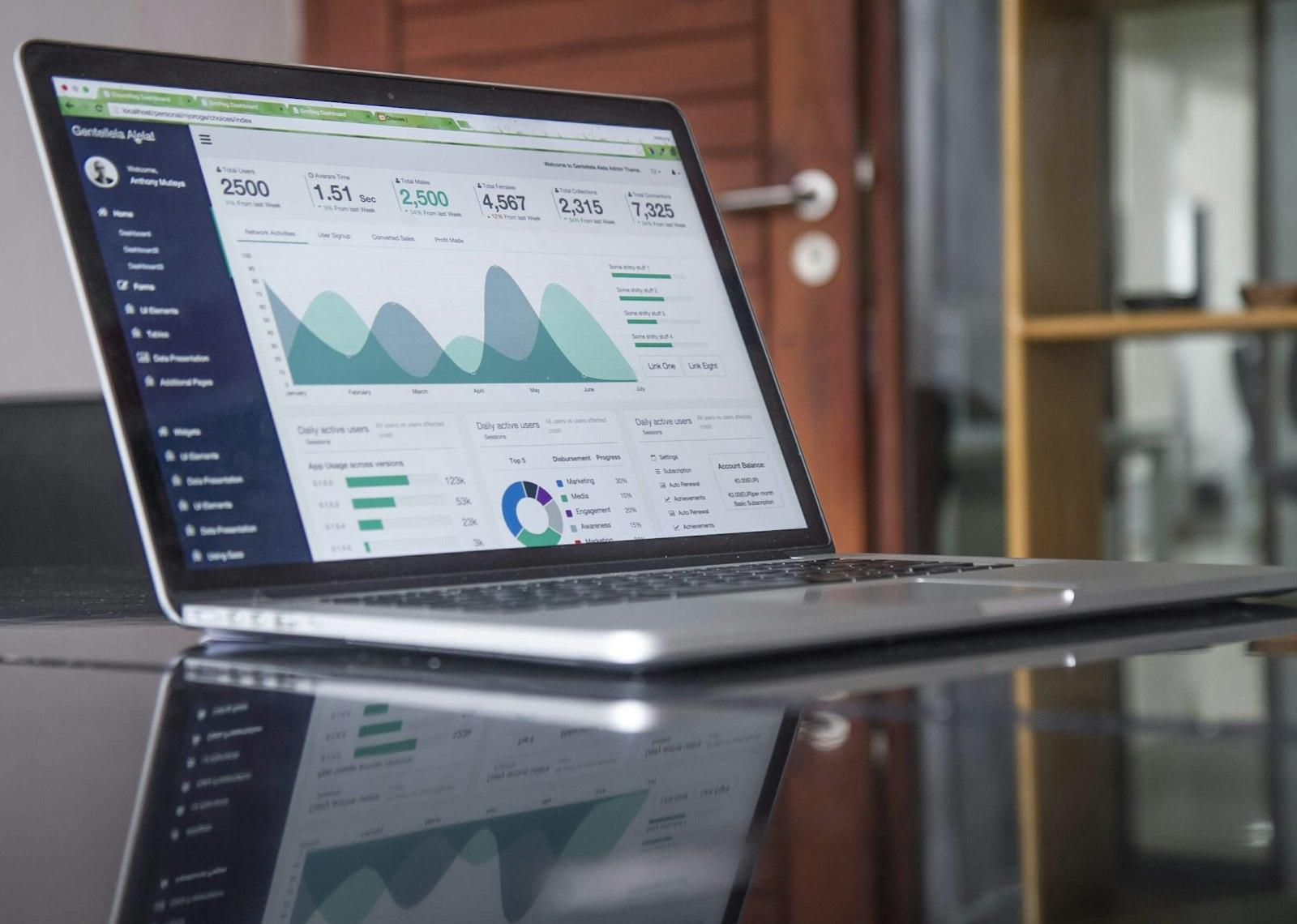 A laptop displaying a green analytics dashboard with charts