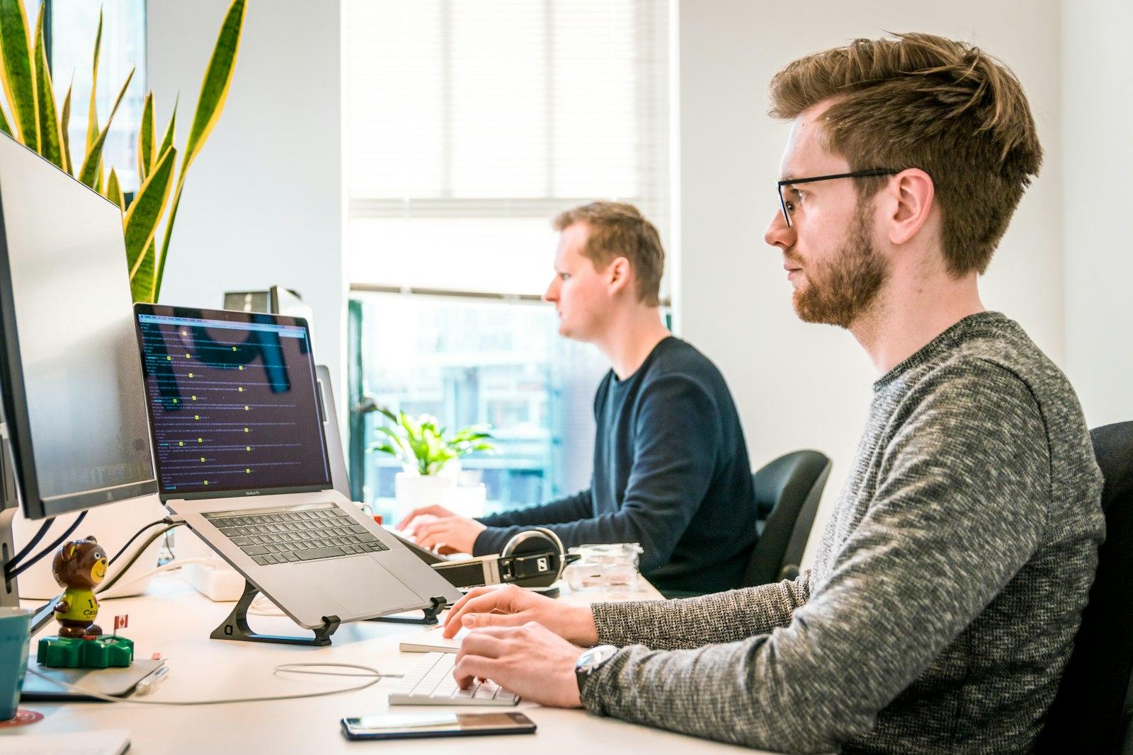 Two people working at desks with an analytics dashboard visible
