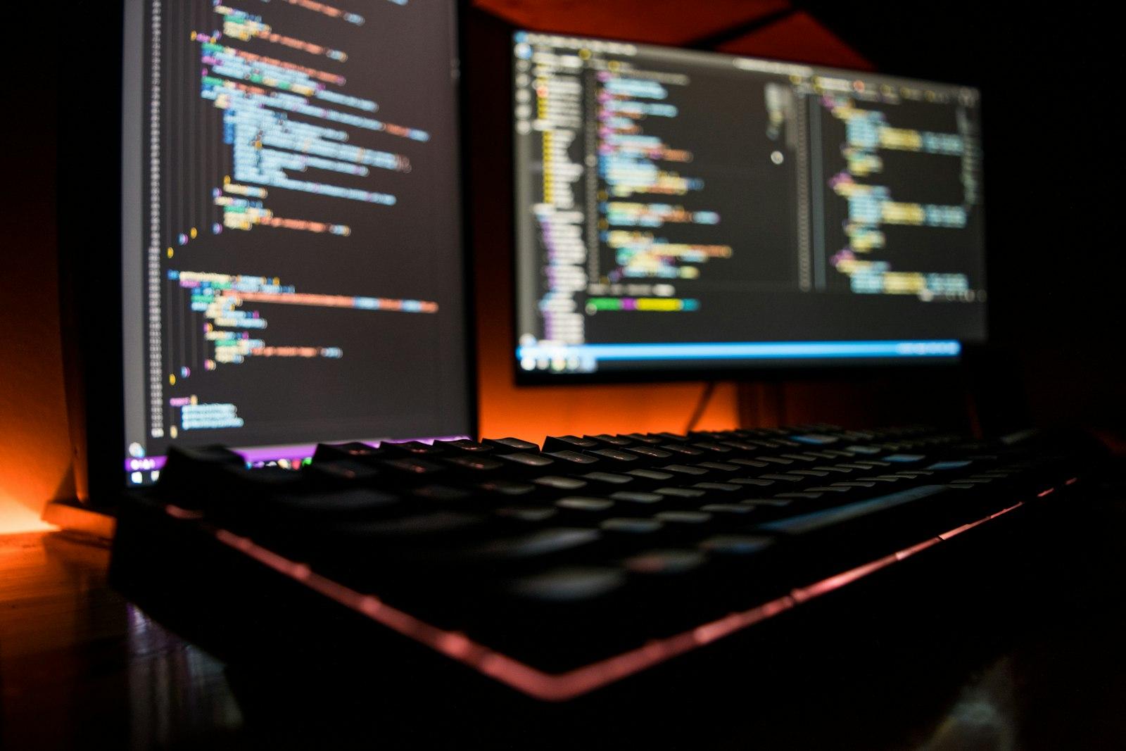 Dark, moody dual monitors showing lines of code