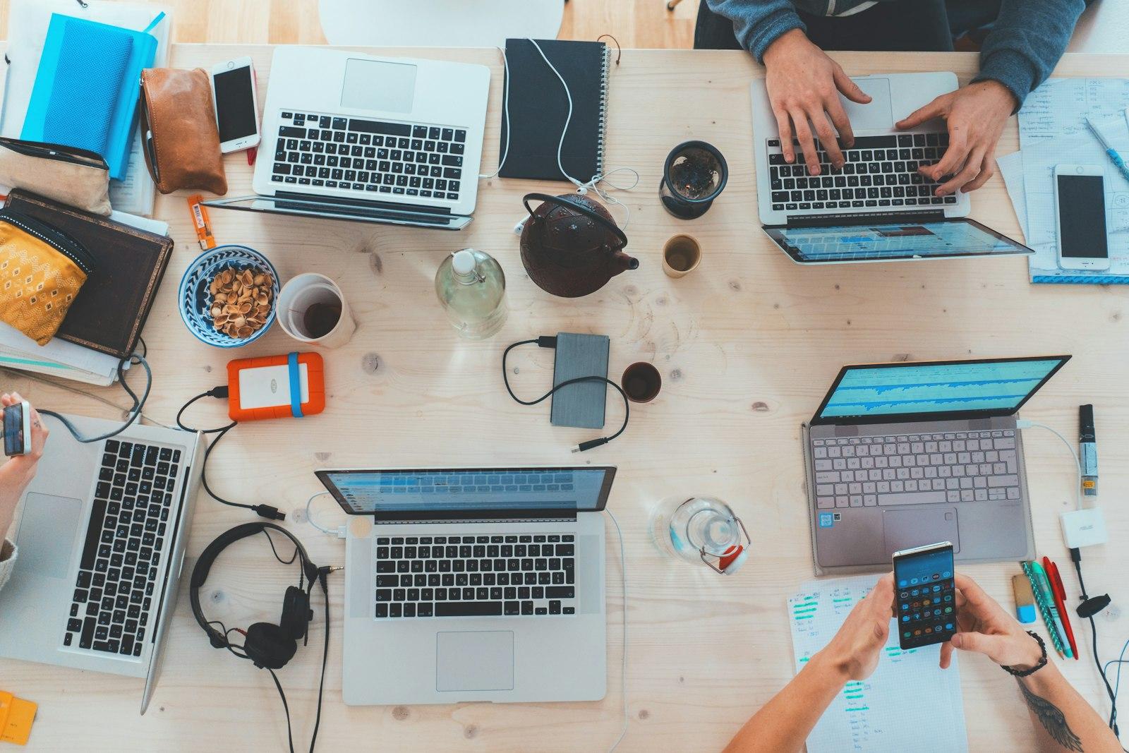 An overhead view of a team working on multiple laptops at a table