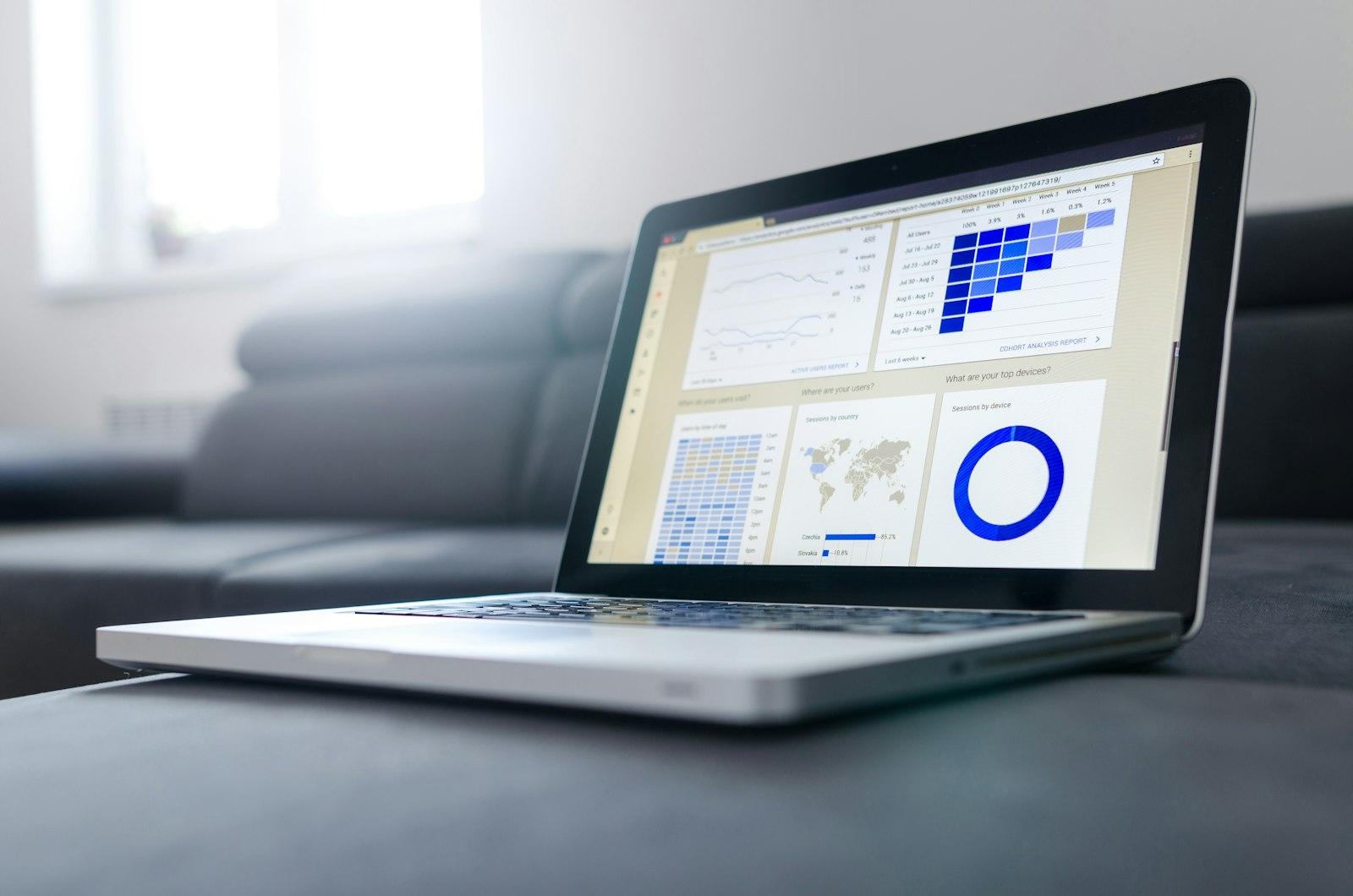 A laptop showing a colorful analytics dashboard on a couch